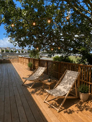 Terrasse extérieure avec guirlande sur un arbre et chaises longues